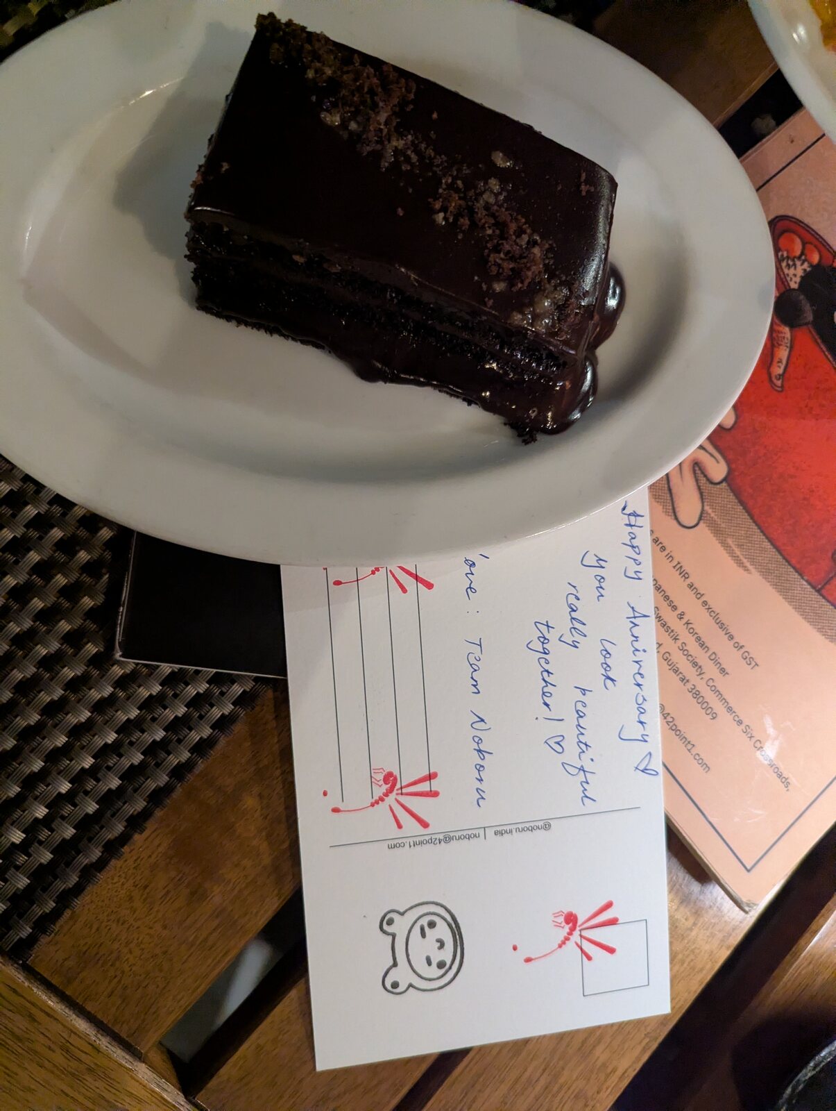 A slice of chocolate cake with a handwritten anniversary note