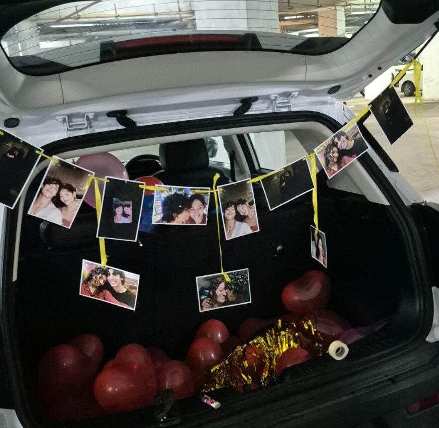 A car decorated with heart balloons and hanging photographs
